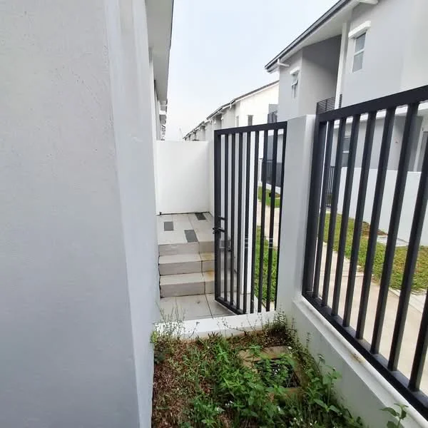 Exterior type: linked terrace house; features: white painted facade, metal gate, concrete steps, landscaped area with grass, surrounding walls, paved walkway, adjacent residential buildings; style: modern.