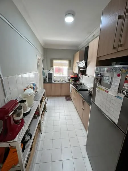 Kitchen features: white tiled flooring, light grey painted walls, laminate cabinetry in light wood finish, black countertop, stainless-steel sink, chrome pull-down faucet, built-in oven, freestanding range oven, microwave, kettle, stand mixer, refrigerator, open shelving, window with blinds, LED ceiling light; style: modern.