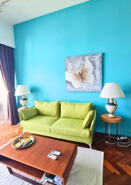 Living features: green fabric sofa, wood coffee table, white area rug, blue accent wall, framed artwork with butterfly design, two table lamps with white shades, wooden side tables, decorative tray on coffee table; style: modern.
