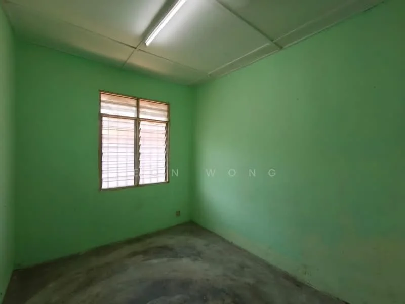 Room features: green painted walls, concrete flooring, single window with wooden blinds, fluorescent ceiling light, plain ceiling.