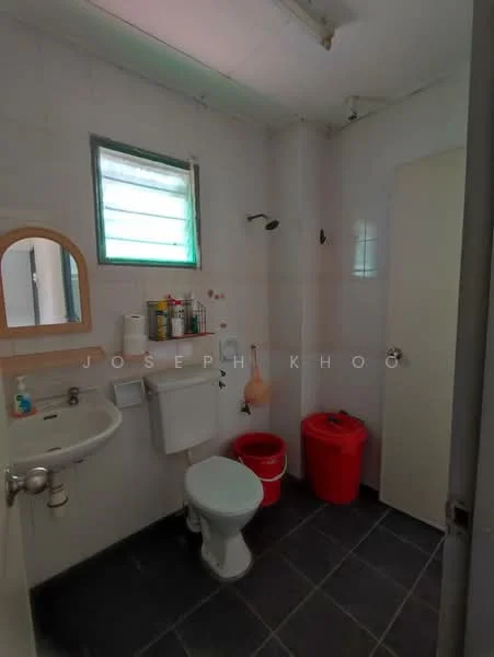 Bathroom features: white tiled walls, grey floor tiles, single-sink vanity with mirror, toilet, shower with wall-mounted faucet, window with green blinds, red waste bin, red storage bin.