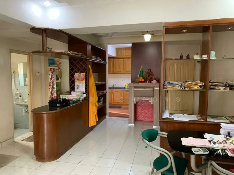 Room features: white tiled flooring, wooden cabinetry, black countertop, built-in wine rack, open shelving, kitchen area with wooden cabinets, sink, decorative statue, wall-mounted light fixture, stacked paperwork, green dining chairs, table with papers, orange fabric hanging, wall with dark accent color; style: traditional.