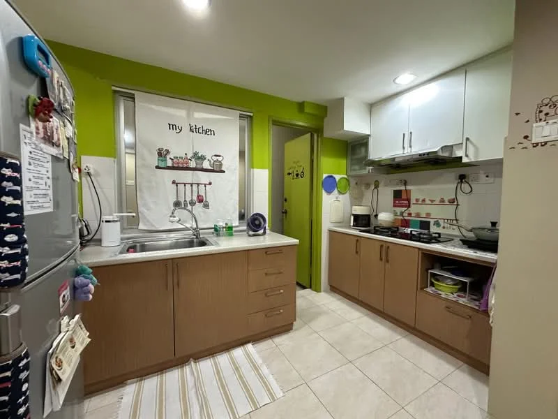 Kitchen features: green painted walls, white upper cabinets, brown lower cabinets, stainless-steel sink, chrome pull-down faucet, white countertop, built-in stove, microwave, refrigerator, kitchen rug, tile flooring, window with sheer curtains, wall-mounted storage, decorative wall art; style: modern.