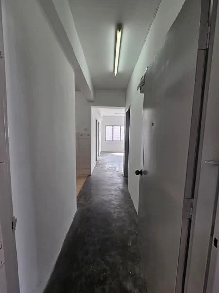 Room features: white painted walls, concrete flooring, fluorescent ceiling light, door with handle, window at the end of the hallway.