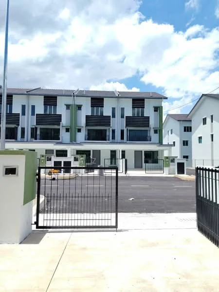 Exterior type: linked terrace house; features: white painted facade, green accent panels, recessed balconies, flat roof, two-storey building, gated entry with metal gate, paved driveway, parking area, surrounded by open space, urban context with nearby buildings; style: modern.