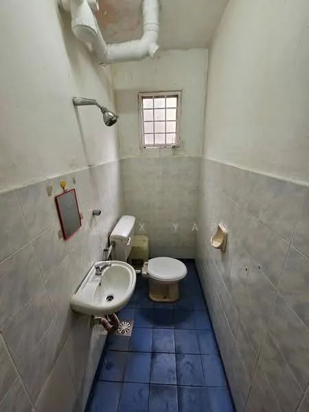 Bathroom features: white tiled walls, blue ceramic tile flooring, single-sink vanity with chrome faucet, one-piece toilet, shower with wall-mounted shower head, small window for natural light, mirror above sink, toilet paper holder.