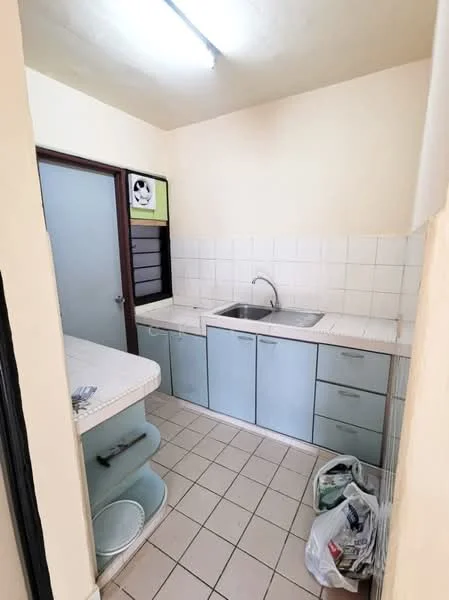 Kitchen features: single-bowl stainless-steel sink, chrome faucet, white tiled backsplash, light blue cabinetry, countertop with overhang, ceramic tile flooring, wall-mounted light fixture, open shelving, waste bin, window with louvered panels.