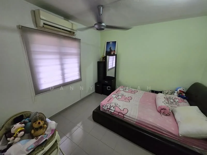 Bedroom features: green painted walls, tile flooring, 1 wall-mounted split AC, 5-blade ceiling fan, double bed with pink bedding, bedside table, mirror on black cabinet, window with sheer blinds, stuffed toys on bed, decorative wall art.
