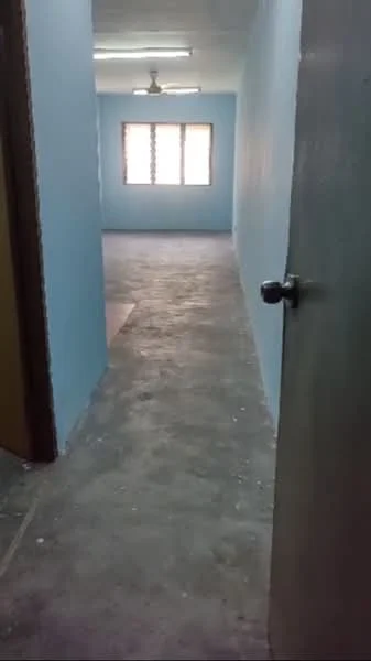 Room features: light blue painted walls, concrete flooring, ceiling fan, window with grille, door with knob, plain ceiling.