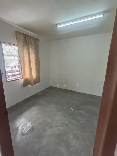 Room features: white painted walls, concrete flooring, single window with curtain, fluorescent ceiling light.