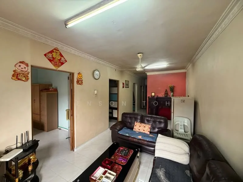 Living features: 3-seater leather sofa in dark brown, coffee table, wall clock, ceiling fan, white tiled flooring, cream painted walls, decorative wall art, light fixture, doorway to adjacent room, window with natural light; style: traditional. Room features: wooden cabinetry, doorway leading to kitchen, light pink wall in adjacent room.