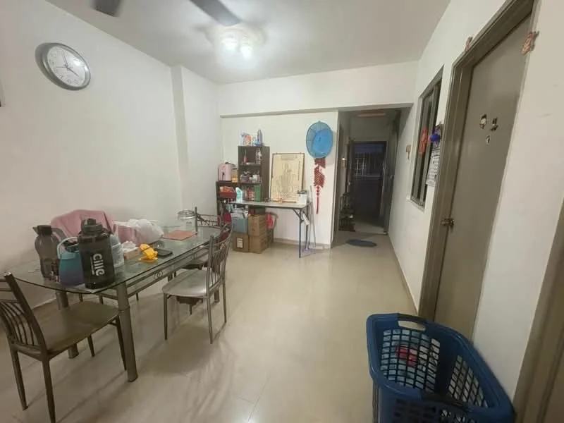 Dining features: glass dining table with metal legs, four metal dining chairs, light-colored tiled flooring, white painted walls, wall clock, open shelving unit, laundry basket, plastic storage containers, kitchenette area visible in background, ceiling fan.