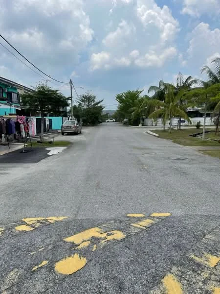 Exterior features: paved road, yellow road markings, surrounding greenery, palm trees, residential buildings in background, clothes hanging on lines, power lines.