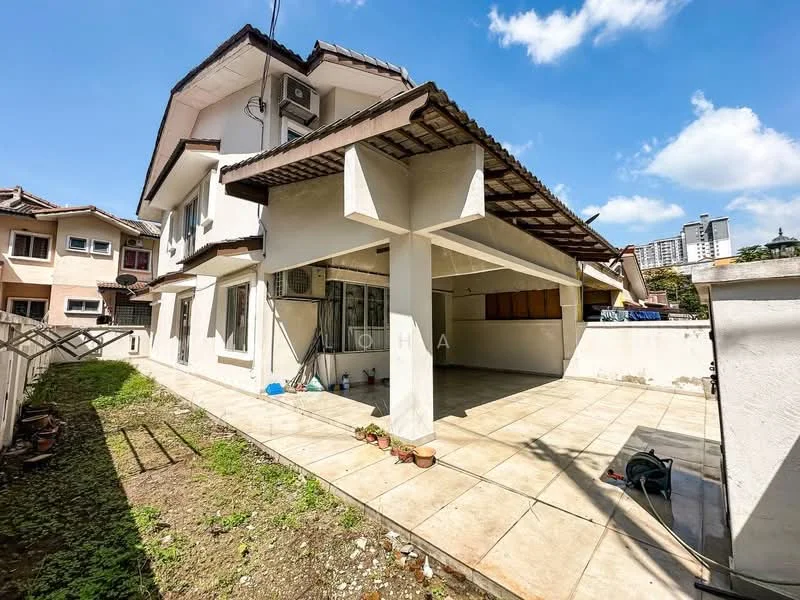 Exterior type: semi-detached house; features: flat roof, white painted facade, exposed concrete columns, large outdoor patio area, tiled flooring, manicured lawn, surrounded by fencing, air conditioning unit visible, adjacent to neighboring houses, urban context with buildings in background; style: modern.