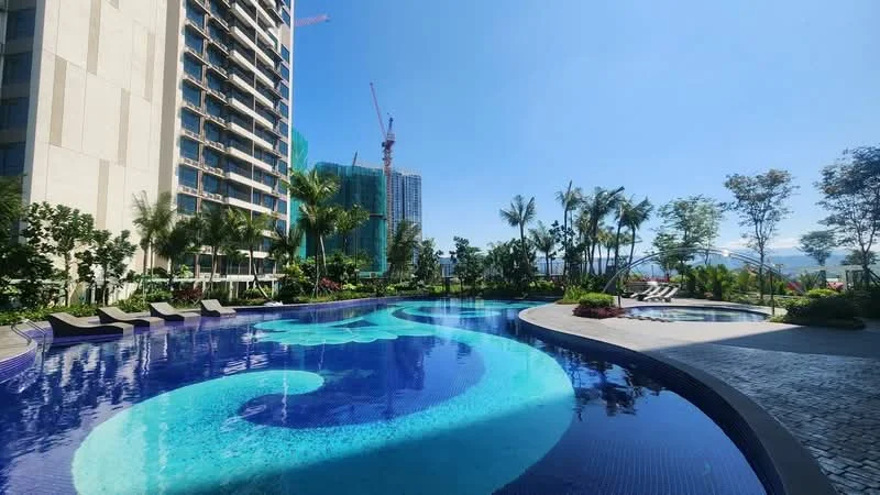 Exterior type: high-rise condominium; features: infinity pool, pool deck with loungers, landscaped garden with palm trees, manicured lawn, surrounded by greenery, city skyline view in background; style: modern.