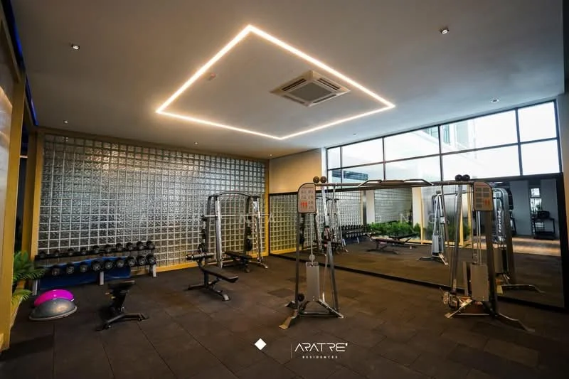Gym features: gym equipment, weightlifting bench, dumbbells on rack, mirrored wall, glass block wall, black rubber flooring, ceiling lights with recessed design, air conditioning unit, indoor plants, large windows for natural light; style: modern; view: garden.