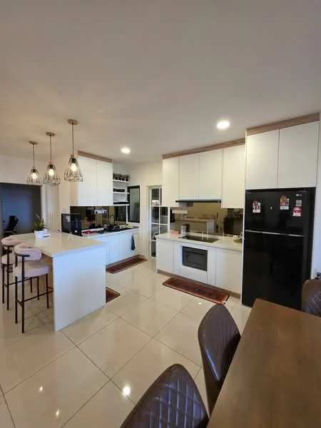 Kitchen features: white cabinetry with flat-panel doors, island with white countertop, stainless-steel built-in oven, stainless-steel microwave, black refrigerator, 4-burner gas hob, black range hood, ceramic tile flooring, pendant lighting above island, glass-front upper cabinets, double-bowl stainless-steel sink, chrome pull-down faucet, decorative area rugs, bar stools at island; style: modern.