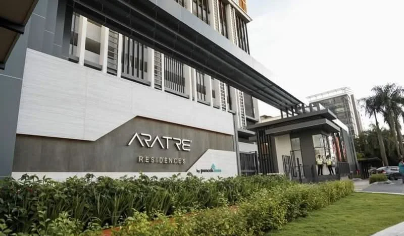 Exterior type: high-rise condominium; features: modern facade with a combination of white and grey surfaces, glass curtain wall, prominent signage with the name 'ARATRE RESIDENCES', landscaped garden with manicured shrubs, paved walkway, entrance with security gate, large windows, balconies visible on upper floors; style: modern.