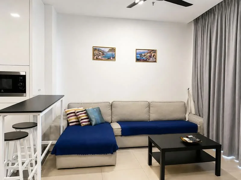 Living features: L-shape sectional sofa in light grey, blue throw blanket on sofa, decorative cushions in various colors, black coffee table, wall-mounted TV, white cabinetry with built-in microwave, bar counter with three white stools, cream tiled flooring, floor-to-ceiling curtains in grey, two framed artworks on the wall, recessed ceiling lights, ceiling fan; style: modern.