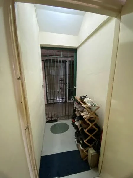 Room features: white painted walls, grey floor tiles, metal security grille, shoe rack, door leading to another space.