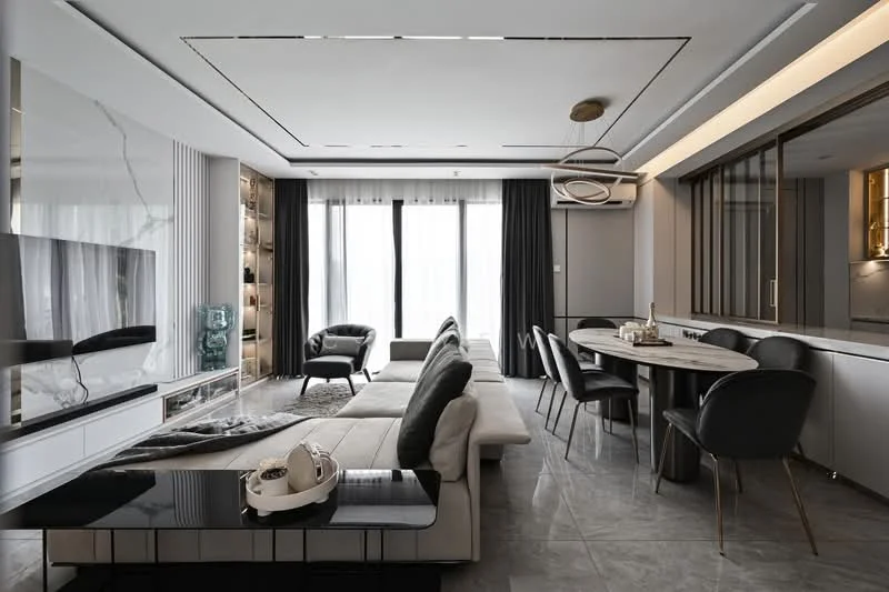 Living features: L-shape sectional sofa in light grey, black coffee table with glossy finish, wall-mounted TV, built-in shelving unit with decorative items, floor-to-ceiling windows with sheer curtains, recessed ceiling lights, ceiling-mounted air conditioning unit, marble tile flooring, decorative wall paneling, dining area with round table and black upholstered chairs, pendant lighting above dining table; style: modern; view: city.