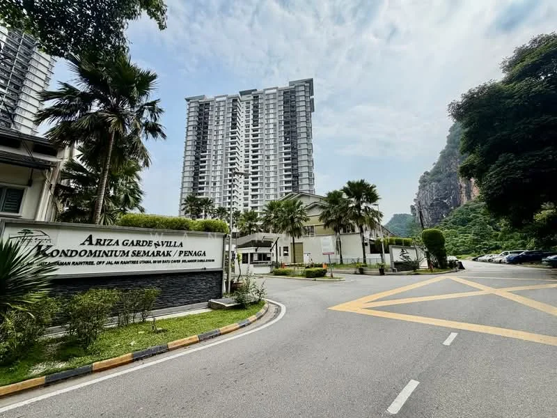 Exterior type: high-rise condominium; features: tall residential building, landscaped entrance, palm trees, manicured lawn, roadway with markings, signage for Ariza Garden Villa, surrounding greenery, mountain backdrop; style: modern.