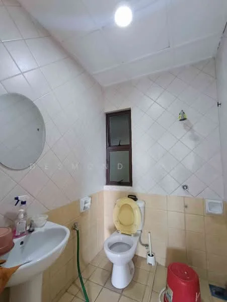Bathroom features: white painted walls, cream tiled flooring, round mirror, single-bowl sink, chrome faucet, toilet with lid, window, shower head, hose connected to sink, bucket, soap dispenser.