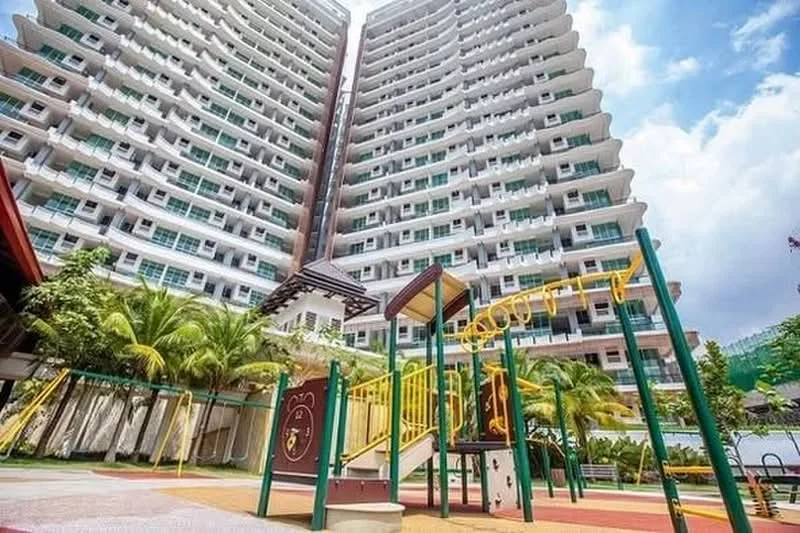 Exterior type: high-rise condominium; features: playground with swings, play structure, manicured landscaping, palm trees, multi-storey building, glass balcony railings, outdoor play area, colorful rubber flooring; style: modern.
