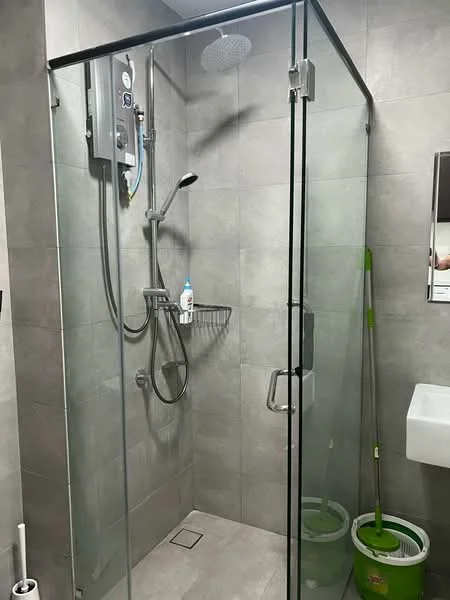 Bathroom features: walk-in shower with glass enclosure, rain shower head, handheld shower, chrome basin mixer, grey tile cladding, built-in shower shelf, toilet brush holder, cleaning bucket, mirror above sink, white sink; style: modern.