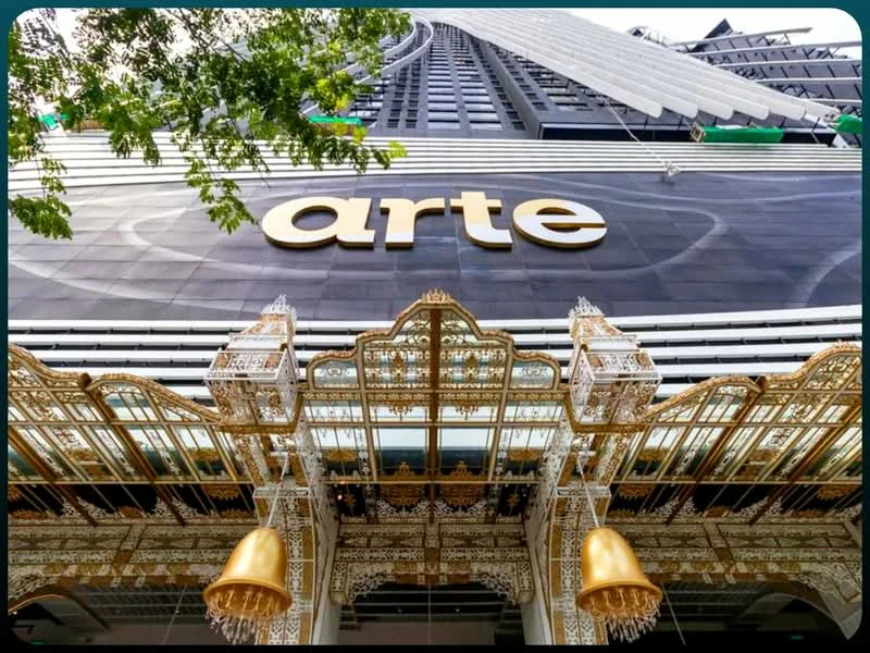 Exterior type: high-rise condominium; features: glass curtain wall, ornate entrance with decorative elements, gold accents, multiple storeys visible, canopy overhang, signage with the name 'arte', modern architectural design; style: modern.