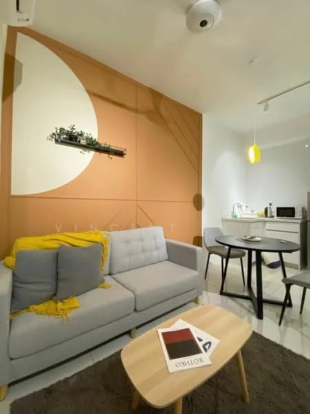 Living features: grey fabric sofa, yellow throw blanket, wooden coffee table, decorative wall shelf with plants, orange accent wall with geometric design, white walls, recessed ceiling lights, pendant light fixture, dining table with two chairs, microwave, kitchenette with sink, kitchen cabinets; style: modern.
