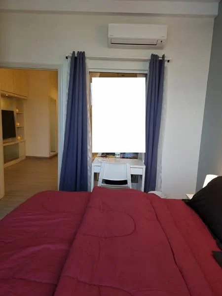Bedroom features: king-size bed with red bedding, wall-mounted split AC, floor-to-ceiling window, dark curtains, light grey painted walls, laminate flooring, study desk with chair, built-in wardrobe, decorative wall art; style: modern.