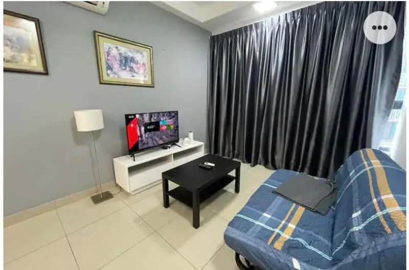 Living features: grey painted walls, white ceiling, tile flooring, 3-seater fabric sofa in blue with plaid pattern, black coffee table, white TV console, wall-mounted TV, floor lamp, black remote control on table, curtains in dark grey; style: modern.