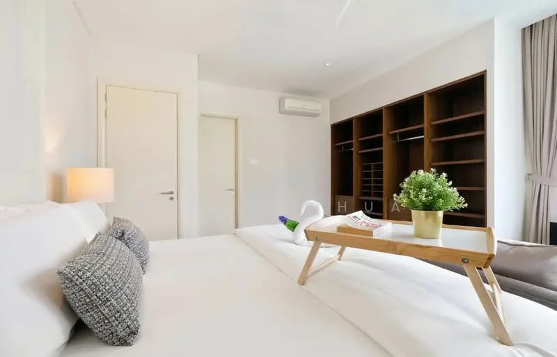 Bedroom features: king-size bed with white bedding, upholstered headboard, 2 decorative pillows, wooden bedside table, table lamp with white shade, built-in wardrobe with open shelving, wall-mounted air conditioning unit, large window with sheer curtains, neutral painted walls, wooden flooring, decorative plant in ceramic pot, breakfast tray on bed; style: modern.