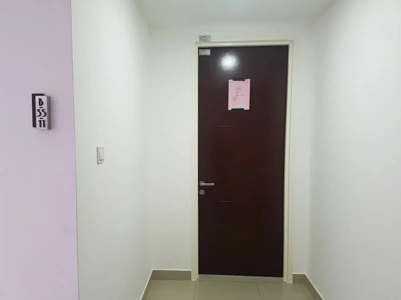 Room features: white painted walls, grey tiled flooring, wooden door, door handle, door number plate, light switch, ceiling light.