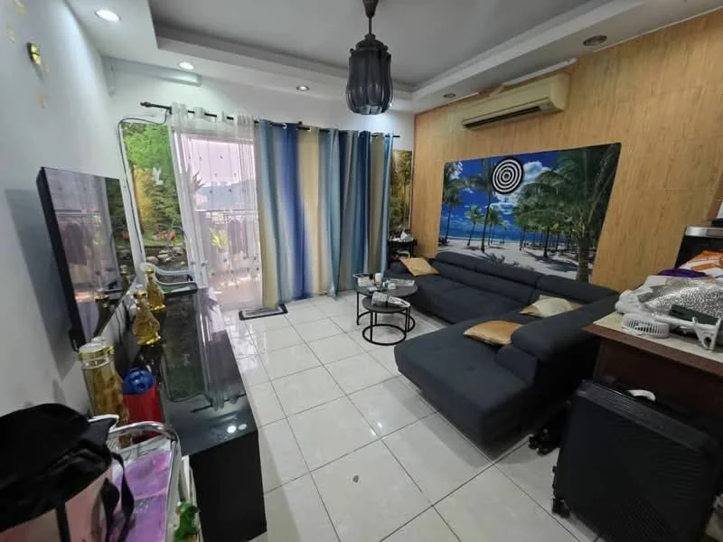 Living features: grey L-shape sectional sofa, coffee table, wall-mounted TV, black TV console, white tiled flooring, recessed downlights, decorative wall art with beach scene, curtains with blue and white stripes, air conditioning unit, sliding glass door leading to balcony, decorative items on console; style: modern; view: garden.