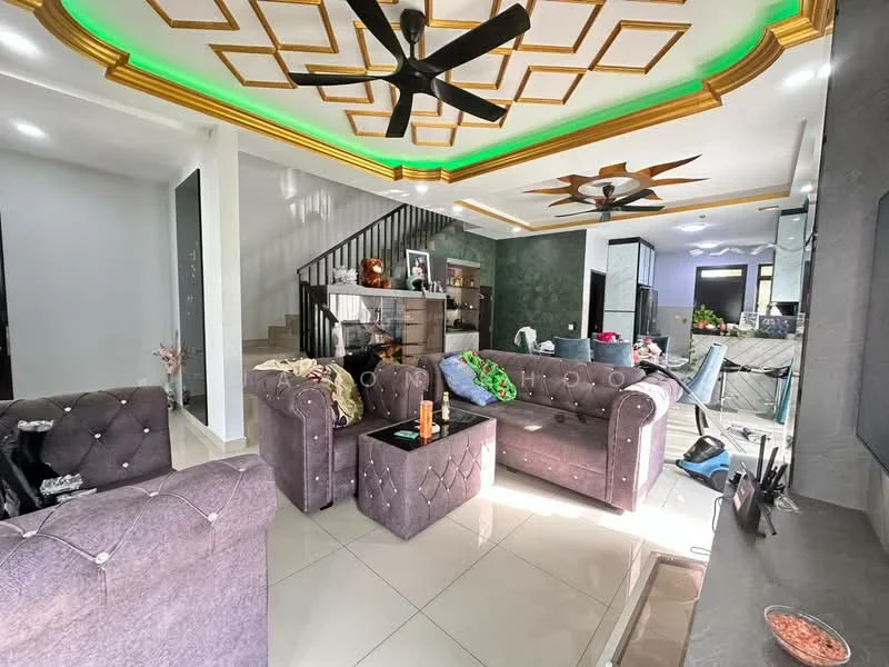 Living features: grey tufted fabric sofas, black coffee table, white tiled flooring, gold tray ceiling with recessed lighting, green LED strip lighting, 2 ceiling fans, decorative wall with dark green finish, staircase with wooden railing, wall-mounted TV, decorative items on shelves; style: modern.