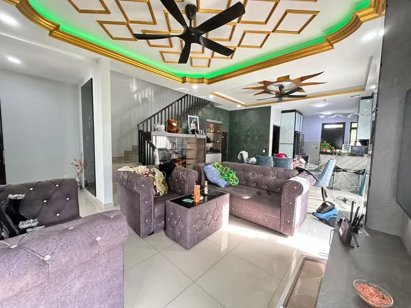 Living features: grey tufted fabric sofas, black coffee table, white tiled flooring, gold tray ceiling with recessed lighting, green LED strip lighting, 2 ceiling fans, decorative wall with dark green finish, staircase in background, wall-mounted TV, decorative items on shelves; style: modern.