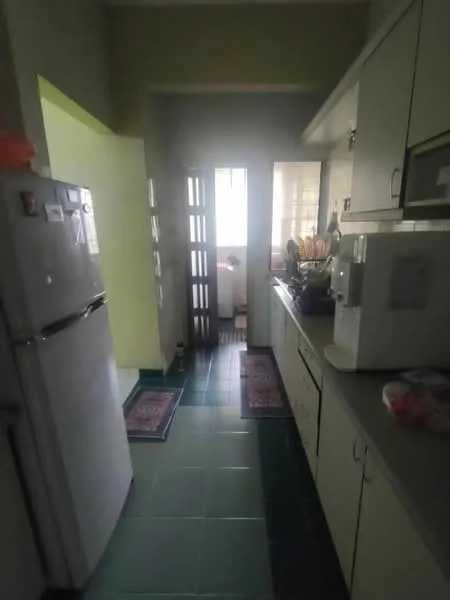 Kitchen features: white cabinetry, grey countertop, stainless-steel fridge, built-in microwave, kitchen sink, ceramic tile flooring in green, two area rugs, window with natural light, door leading to balcony, wall-mounted shelves.