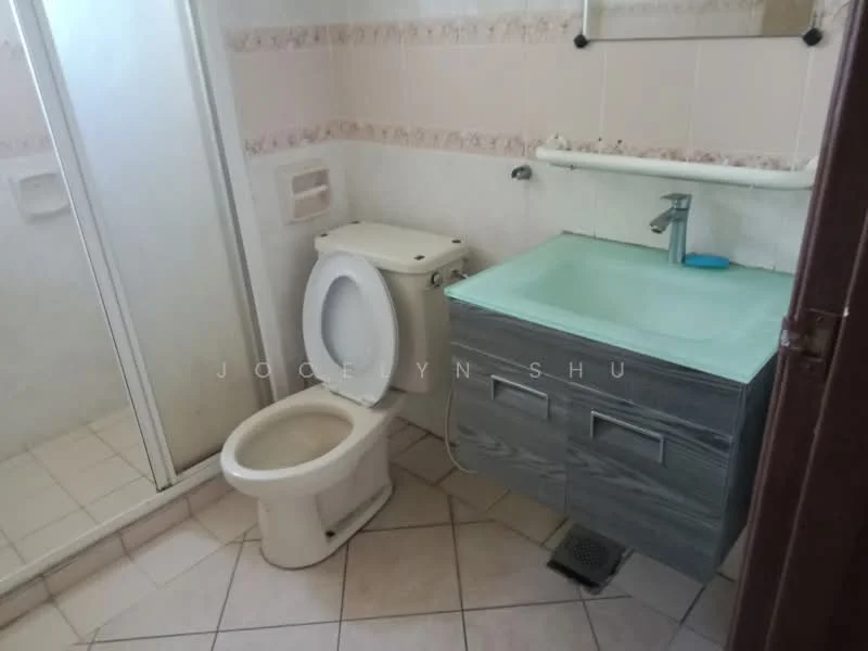 Bathroom features: white toilet, single-sink vanity with grey cabinet, light blue countertop, shower enclosure with glass door, tile flooring, wall-mounted mirror, towel rail, white wall tiles with decorative border, floor drain.