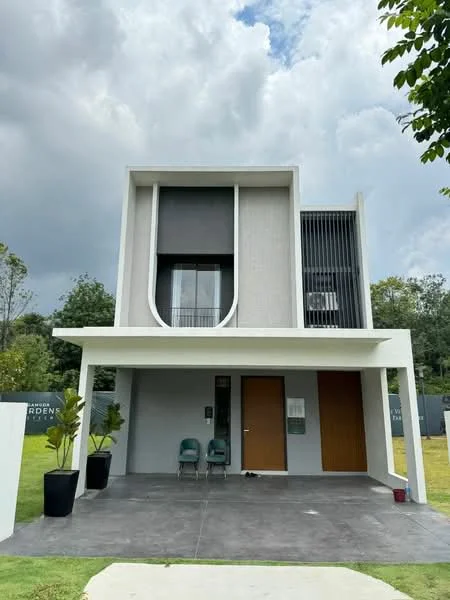 Exterior type: detached bungalow; features: white painted facade, flat roof, two-storey structure, large windows, vertical fins on facade, manicured lawn, concrete driveway, potted plants at entrance, double main entrance doors, porch area with seating, surrounded by greenery; style: modern.