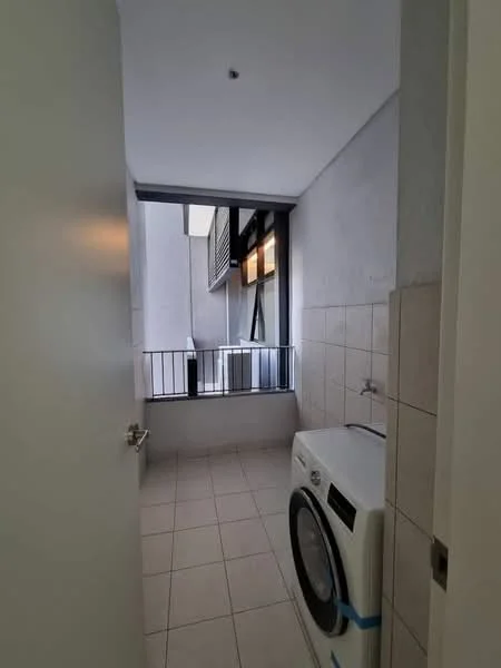 Laundry features: white front-load washing machine, grey tiled flooring, light grey painted walls, window with black railing, natural light from window, water tap, wall-mounted shelf, space for additional storage; style: modern.