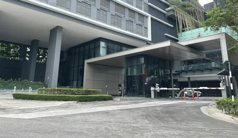 Exterior type: high-rise condominium; features: glass curtain wall facade, grey painted facade, recessed balconies, landscaped entrance with greenery, driveway with interlocking pavers, security boom gate, covered entrance, multiple storeys, modern architectural design; style: modern.