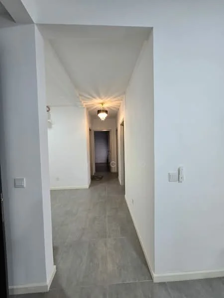 Hallway features: white painted walls, grey tile flooring, chandelier light fixture, recessed ceiling lights, doorways leading to other rooms, neutral color scheme, baseboards, smooth ceiling; style: modern.