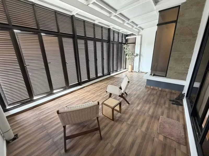 Room features: wooden flooring, white painted walls, sliding glass doors, horizontal wooden blinds, exposed beams ceiling, two chairs, small side table, decorative plant, stone feature wall, area rug; style: modern.