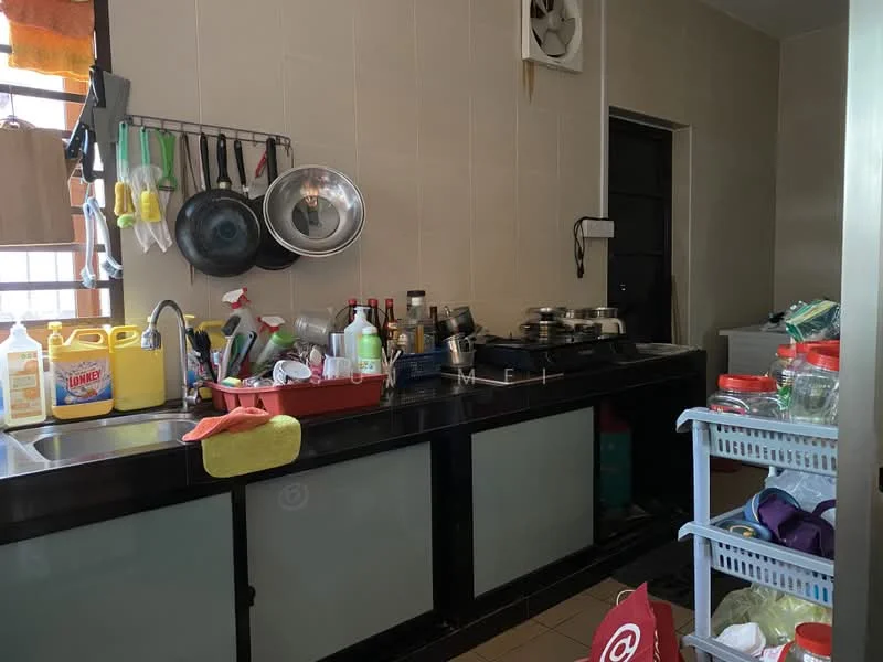 Kitchen features: black countertop, stainless-steel sink, wall-mounted split AC, cooking pots and pans, various bottles and containers, dish rack with dishes, plastic storage containers, kitchen utensils hanging, cabinets with glass doors, tile flooring, cream painted walls.