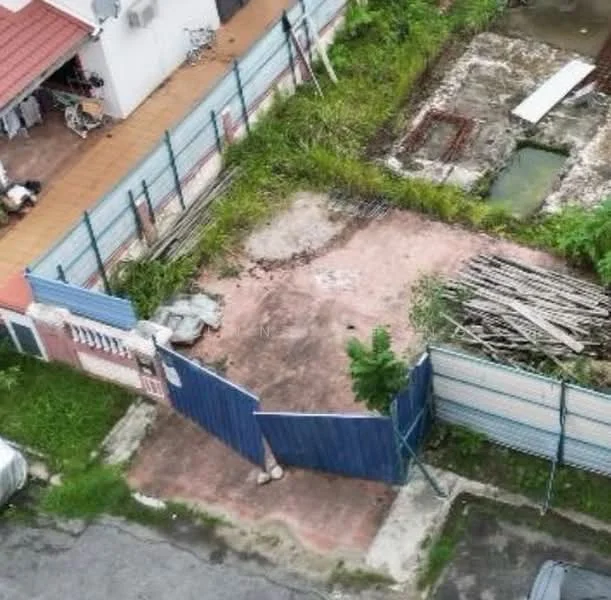 Exterior features: fenced perimeter, paved driveway, overgrown grass, construction debris, gated entry, adjacent residential building, open space, partially cleared land.