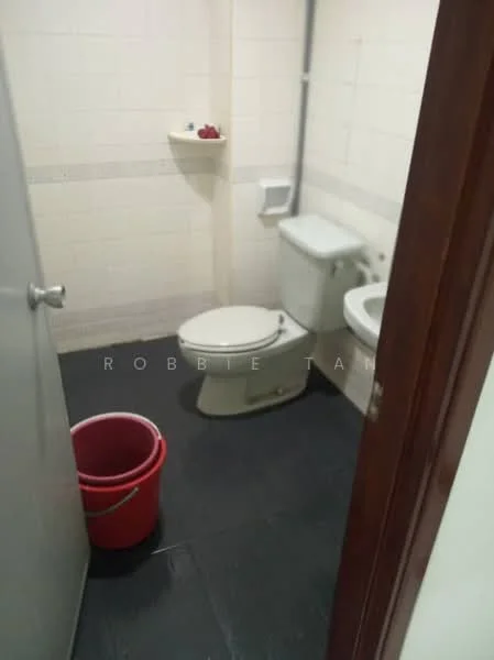 Bathroom features: white tiled walls, black tile flooring, one-piece toilet, sink with faucet, shelf above toilet, red plastic bucket.