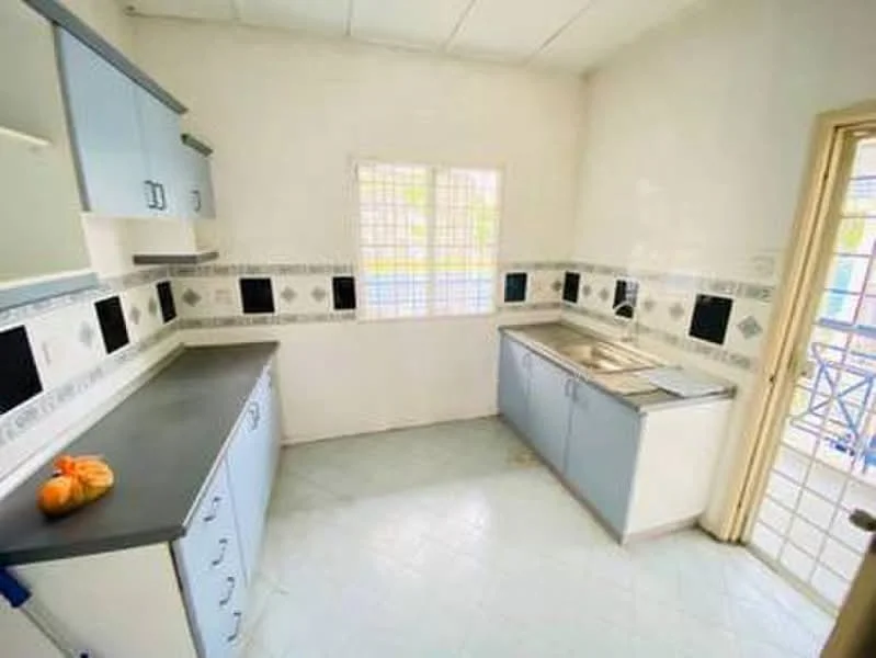 Kitchen features: blue cabinetry, grey countertop, double-bowl stainless-steel sink, chrome pull-down faucet, wall tiles with black and white accents, white painted walls, tile flooring, window with grid pattern, kitchen layout with L-shape.
