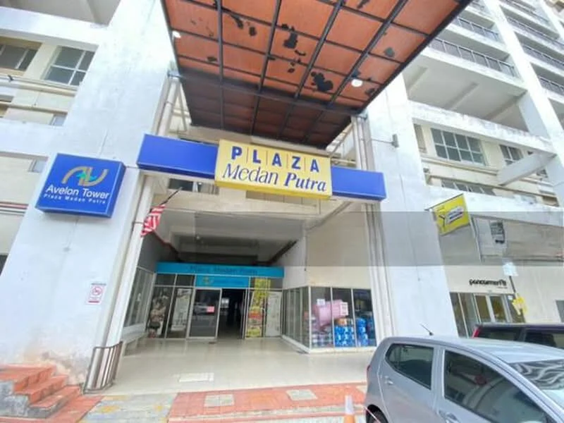 Exterior type: mid-rise condominium; features: signage with 'PLAZA Medan Putra', entrance with awning, glass doors, visible retail spaces, parking area, surrounding concrete structure, multiple storeys, sidewalk access; style: modern.